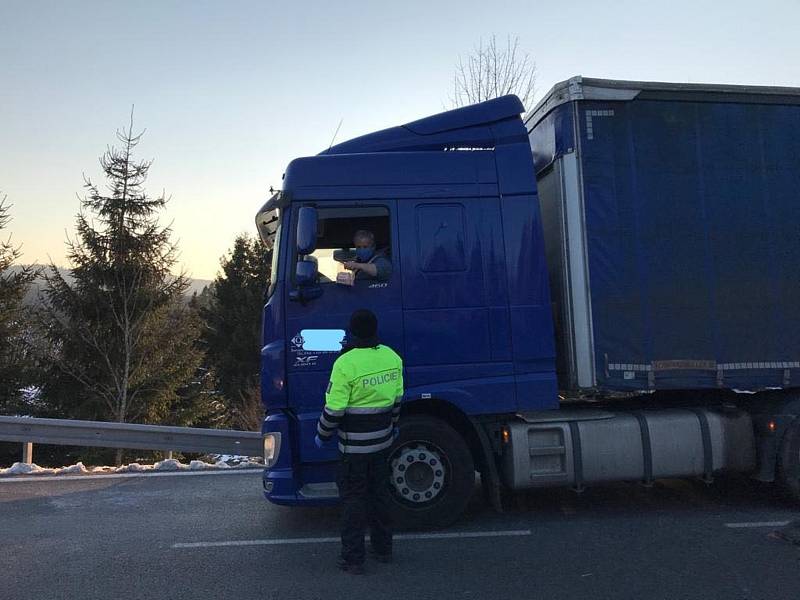 Policisté předávají roušky na hraničních přechodech.