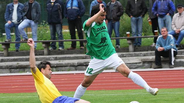 Obě sestavy byly v derby poznamenány marodkou a absencemi hráčů základu, ale méně to vadilo Českokrumlovským. Na snímku hostující veterán, dvaačtyřicetiletý Václav Anderle, skluzem zastavuje průnik autora třetí branky domácích Ondřeje Benčiče.