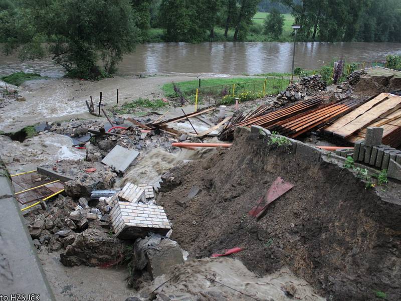 Voda s bahnem valící se v sobotu odpoledne dolů rájovským kopcem tady poškodila silnici, most i vedle stojící dům.