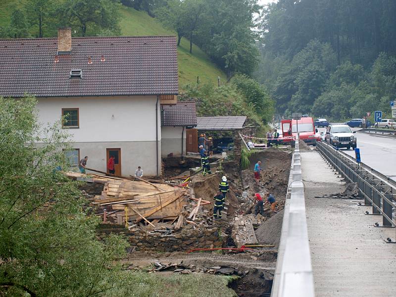 Voda s bahnem valící se v sobotu odpoledne dolů rájovským kopcem tady poškodila silnici, most i vedle stojící dům.