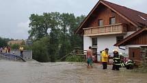 Voda s bahnem valící se v sobotu odpoledne dolů rájovským kopcem tady poškodila silnici, most i vedle stojící dům.