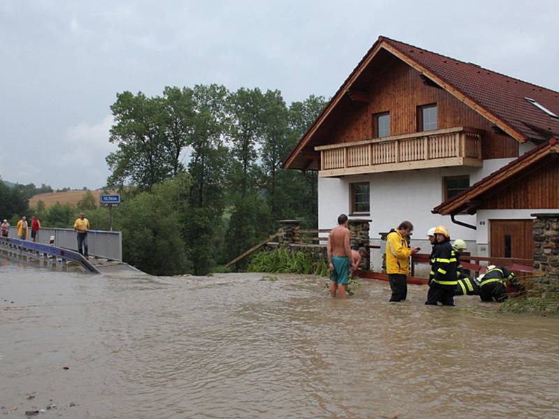 Voda s bahnem valící se v sobotu odpoledne dolů rájovským kopcem tady poškodila silnici, most i vedle stojící dům.