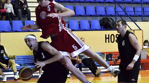 Na strakonické palubovce nebyl k vidění příliš pohledný basketbal, ale kaplický favorit si nakonec pro „povinné“ body přece jen dokráčel. V této chvíli se hostující Lukáš Hejný (č. 11) snaží prosadit přes akrobaticky zasahujícího domácího Bůžka.