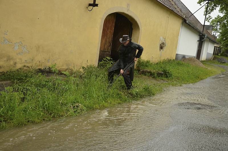 Ondřej Posejpal čistí v Pořešíně stoku, aby voda netekla po silnici.