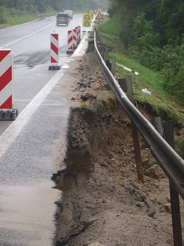 Voda s bahnem valící se v sobotu odpoledne dolů rájovským kopcem tady poškodila silnici, most i vedle stojící dům.