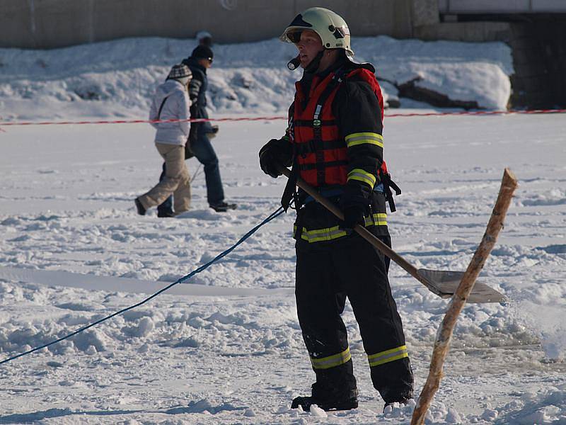 Předtím, než hasiči vytáhli na břeh jezera potopený automobil, museli vyčistit led od sněhu a v ledu vyříznout pás od místa, kde se vůz probořil do vody, až ke břehu.