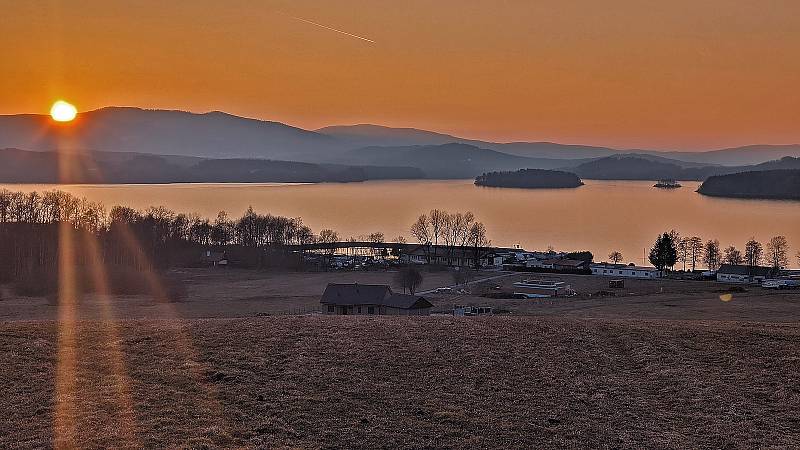 Krásné pohledy na Lipno jsou z kempu Jestřábí v Černé v Pošumaví - rozlehlá vodní plocha s ostrovem v pozadí a nad nimi se tyčící nejvyšší vrchol Šumavy - Plechý.