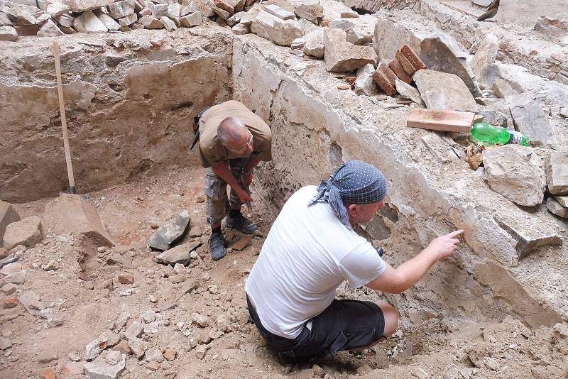 Bádání archeologů během rekonstrukce renesančního paláce na Helfštýně. Členové archeologického týmu studují relikty heraldické výzdoby na nejstarší omítce místnosti.