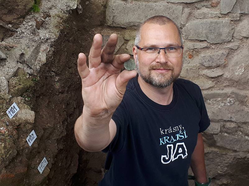 Asistent archeologického výzkumu Miroslav Komínek s nalezeným početním žetonem vyrobeným v Norimberku.