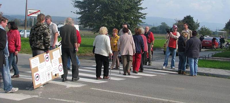 Upozornit na obrovské množství nákladních aut, která projíždějí přes obec Prosenice, se místní lidé pokusili v úterý pomocí blokády. Více než půl hodiny chodili s transparenty přes přechod pro chodce a auta musela čekat nebo se otáčet.