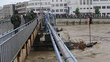 Hasiči odstraňují naplavené kusy dřeva u Tyršova mostu.