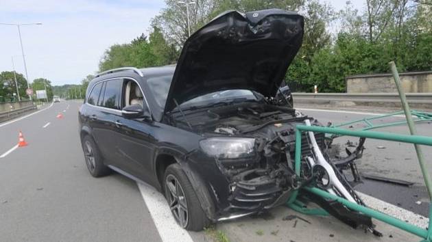 Nehoda v Bělotínské ulici v Hranicích, 22. 5. 2022. Mercedes Benz narazil do zábradlí a poničil dopravní značku, jejíž kusy zasáhly projíždějící BMW