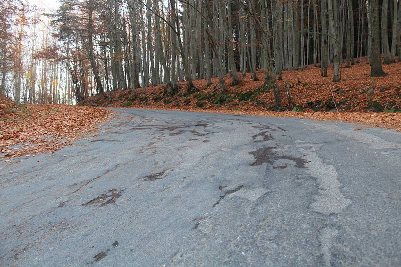 Silnice z Modré na Bunč je místy popraskaná a záplatovaná s prohlubněmi a drolící se krajnicí.