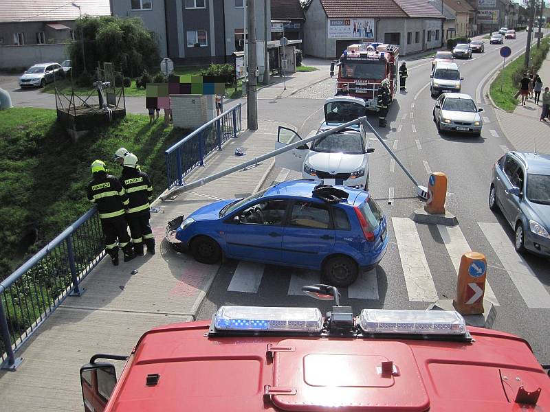 Jedno auto vyjelo z komunikace a narazilo do zábradlí a sloupu veřejného osvětlení. Ten se podlomil a poškodil ještě druhé vozidlo, které jelo v těsné blízkosti havarovaného automobilu.