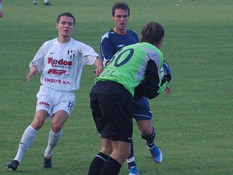 Brankář Slovácka Marek svírá v náruči míč před dotírajícím olomouckým útočníkem Korčianem.   