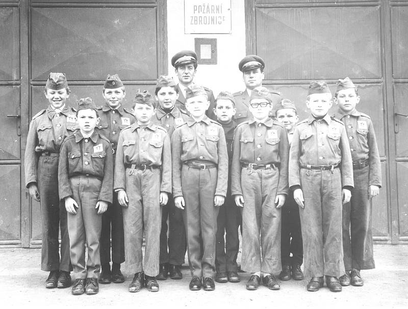 HASIČI PŘED ZBROJNICÍ. Mladí hasiči na sklonku 60. let minulého století nastoupeni před hasičskou zbrojnicí.