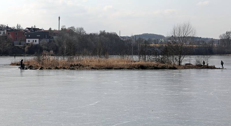 Ledová Praha - zamrzlý Kyjský rybník. Lidé si přes něj zkracují cestu na vlak, maminky bruslí s kočárkem a hraje se tu hokej.