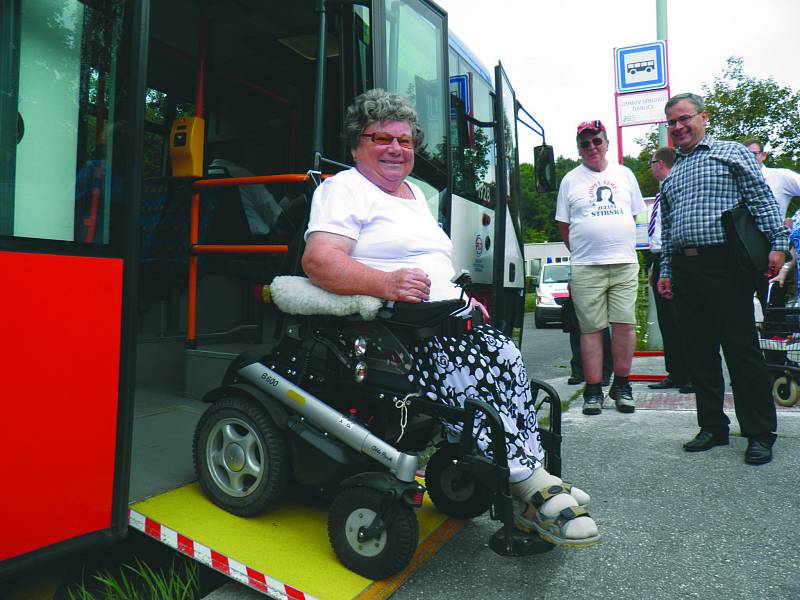 Seniorka vystupuje ze speciálního autobusu.