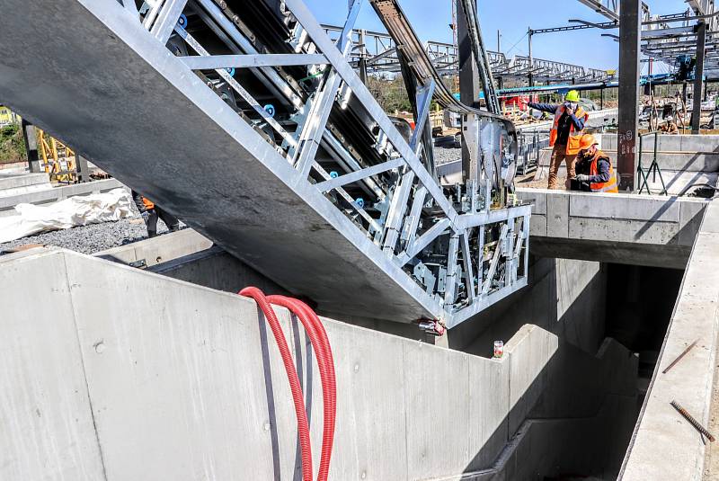 Do nového mostu přes Průběžnou ulici byly instalovány eskalátory, které povedou k železniční zastávce Praha-Zahradní Město.