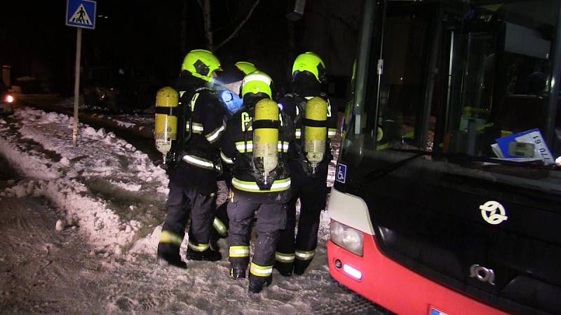 Hasiči pomáhají obyvatelům do evakuačního autobusu.