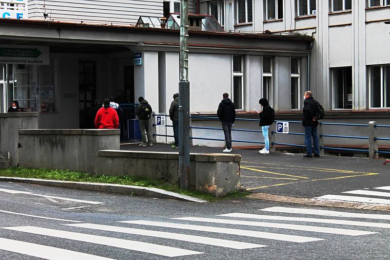 Lidé čekají v Nemocnici Na Bulovce ve frontě na odběr vzorků kvůli novému koronaviru.