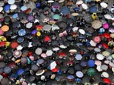 Lidé se schovávali ve čtvrtek 21. července 2011 při celodenním dešti v centru Prahy pod deštníky.