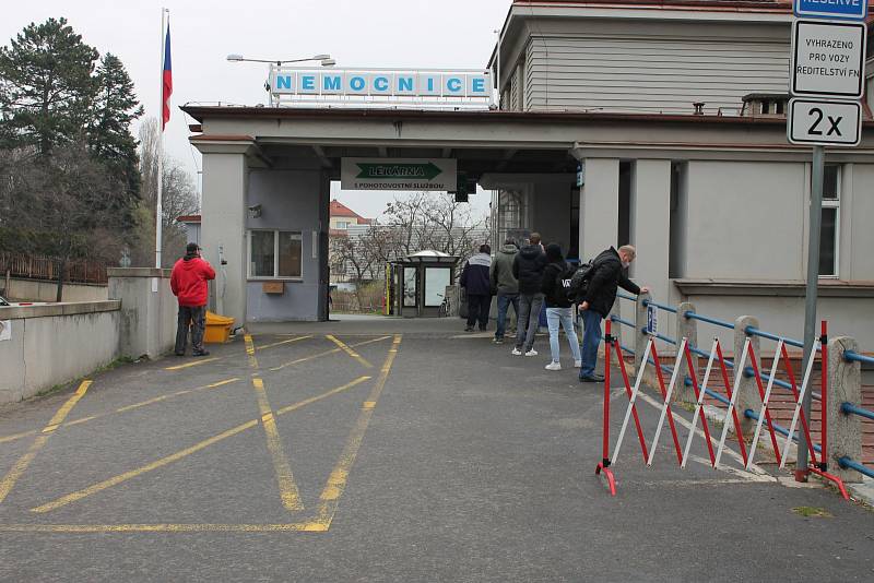Lidé čekají v Nemocnici Na Bulovce ve frontě na odběr vzorků kvůli novému koronaviru.