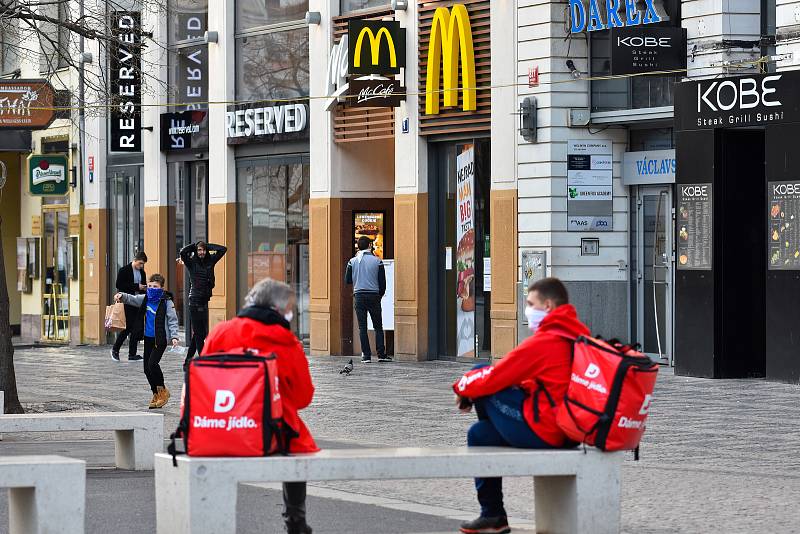 Prázdné ulice Prahy a lidé s rouškami 18. března 2020. Kurýři na rozvoz jídla čekají na objednávku.