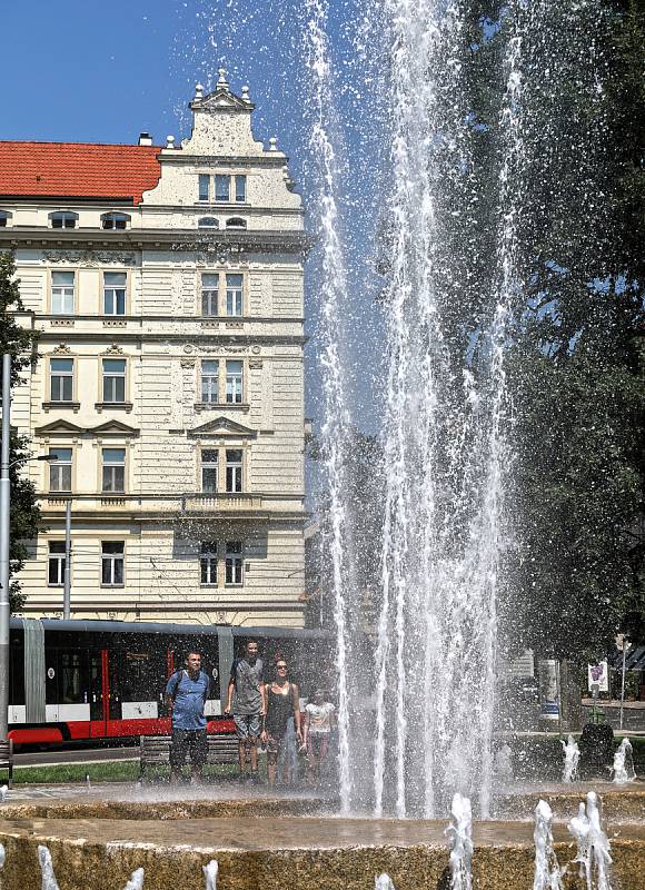 Tropické počasí v Praze. Fontána před Justičním palácem na Smíchově slouží lidem jako osvěžující malé koupaliště.