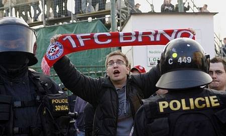 Policejní těžkooděnci oddělují fanoušky Brna od fanoušků Bohemians u jejich stadionu v Praze - Vršovicích.