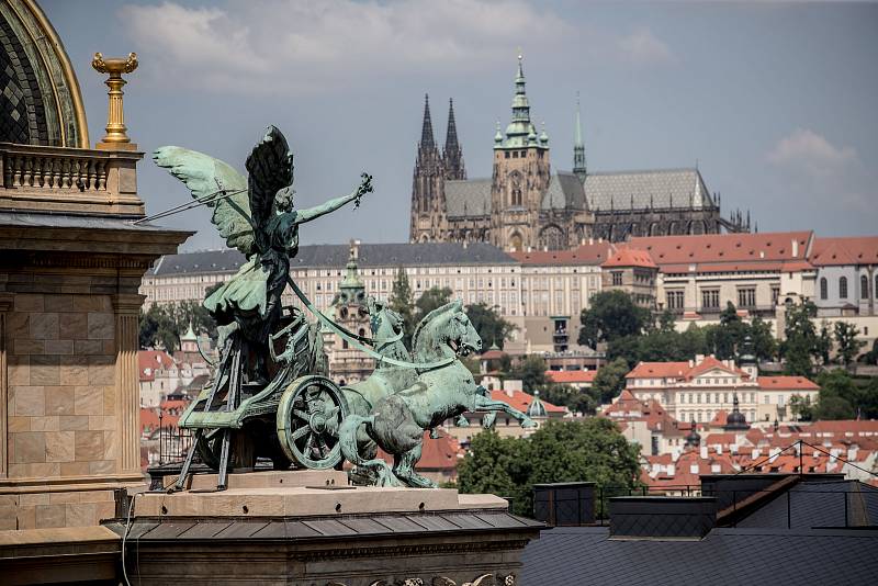 Pohled na trigy na budově Národního divadla a v pozadí Pražský hrad 25. května v Praze.