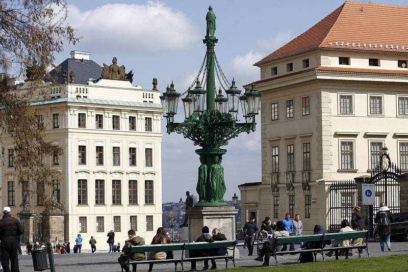 Osmiramenný kandelábr na Hradčanském náměstí byl stejně jako předcházející odlit v Komárovských železárnách roku 1865 podle návrhu architekta Alexeje Linsbauera a sochaře a řezbáře Edvarda Veselého.