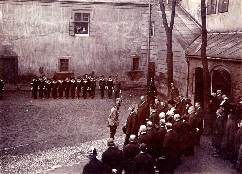 Arcivévoda Karel František Josef se zdraví s kanovníkem a novojičínským děkanem Johannem Parschem, v otevřeném okně na vše shlíží arcivévodkyně Zita se svou dvorní dámou. 