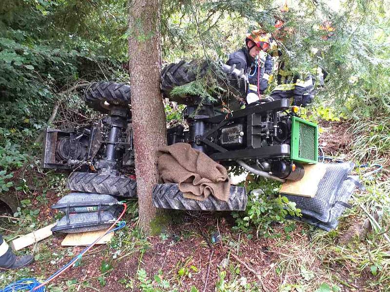 Několik jednotek hasičů zasahovalo při nehodě traktoru, který se v nepřístupném terénu zřítil ze srázu z lesní cesty.