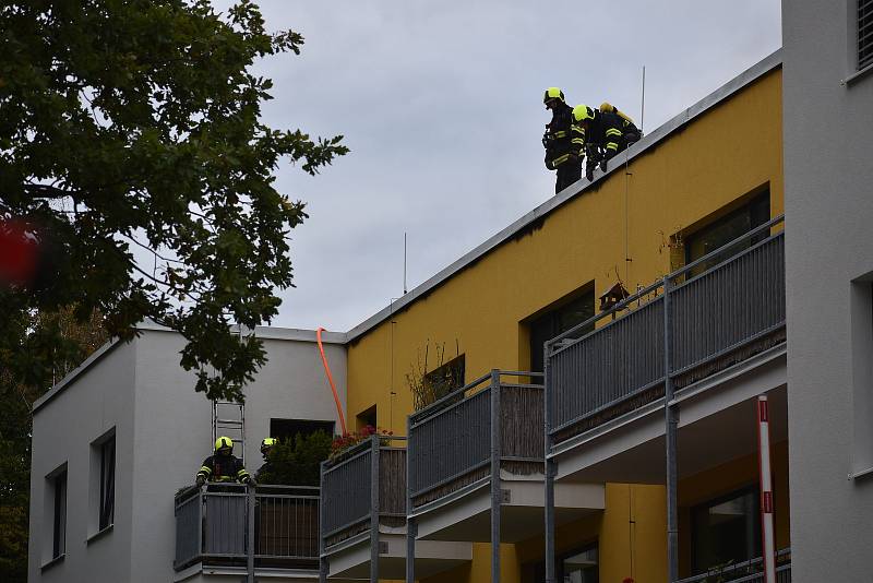 Hustý dým valící se ze střechy a silný zápach. V adamovské ulici Ronovská začalo v pondělí hořet v jedné z tamních bytovek. Podle prvotních informací hasičů se oheň snažili před pátou hodinou odpoledne uhasit hadicí dělníci, kteří na střeše domu pracovali