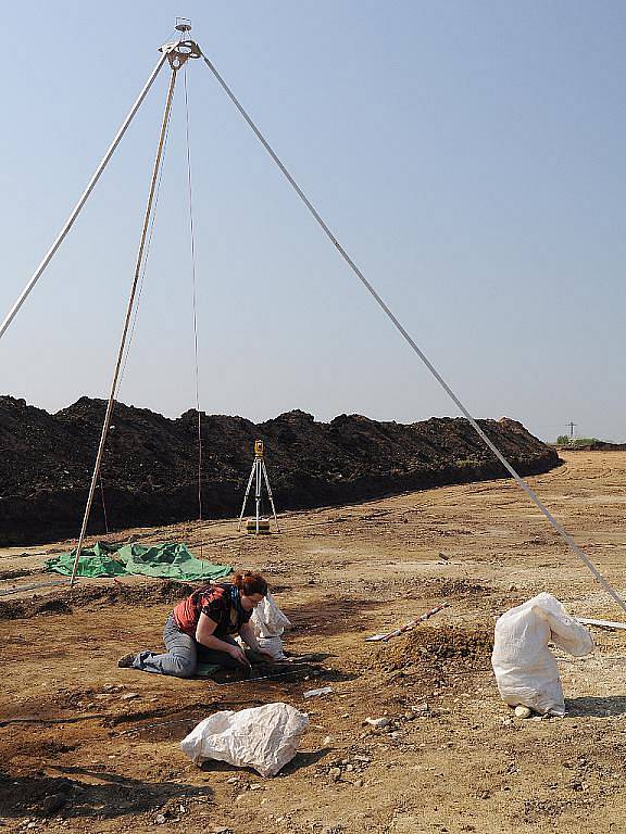 Preparace objektu v rámci archeologického výzkumu. V pozadí věž na fotografickou dokumentaci a geodetický měřicí přístroj.