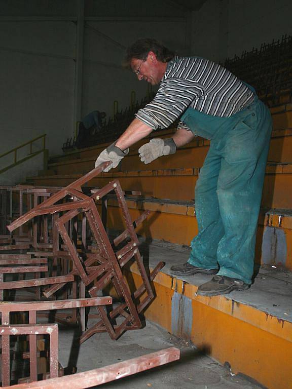 Dělníci demontují staré sedačky na tribunách břeclavského zimního stadionu.