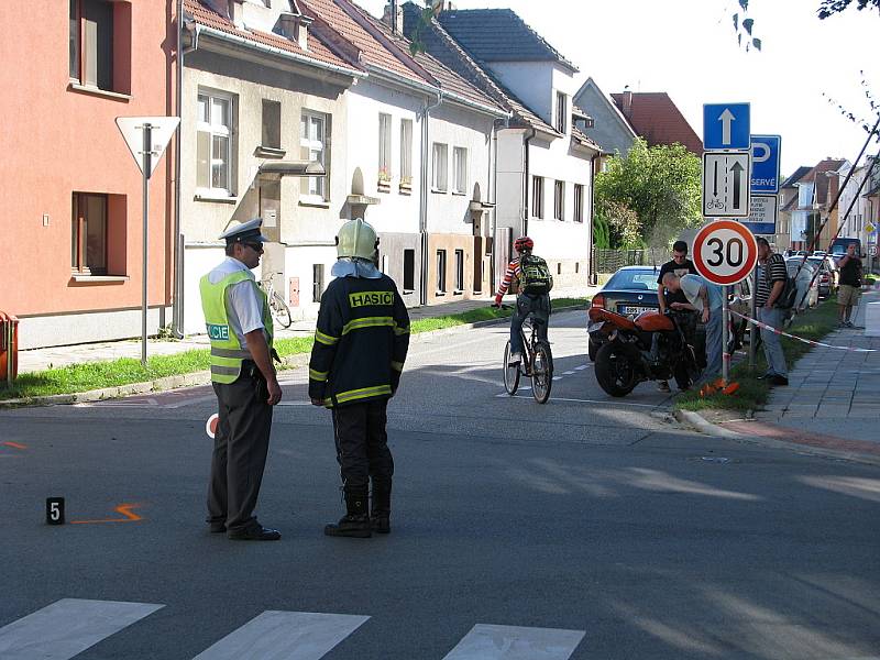 V místě nehody na křižovatce ulic Sladová, Fintajslova a Čermákova řídí policisté dopravu a hasiči zasypávají uniklé pohonné kapaliny sorbentem.