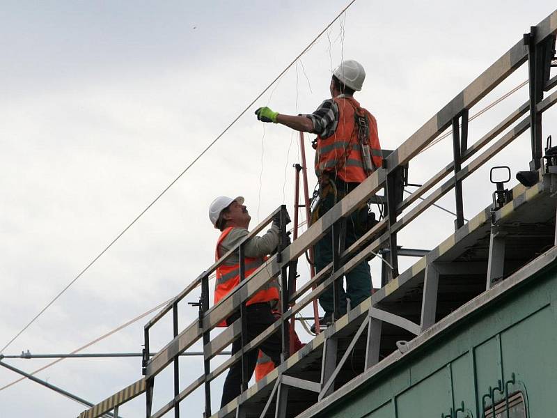 Dělníci natahují posledních pár metrů elektrického trakčního vedení. 