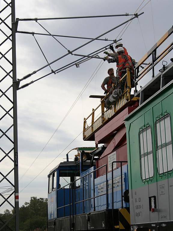 Dělníci natahují posledních pár metrů elektrického trakčního vedení. 