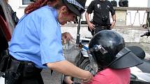 Strážnice městské policie předvádí malé zájemkyni ochrannou přilbu a štít.