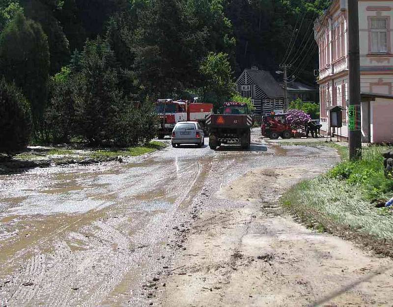 Během noční bouřky voda zaplavila náves ve Velenicích. Ráno zbyly po deštích nánosy bahna, které odklízeli pracovníci krajské správy silnic a dobrovolní hasiči ze Zákup.