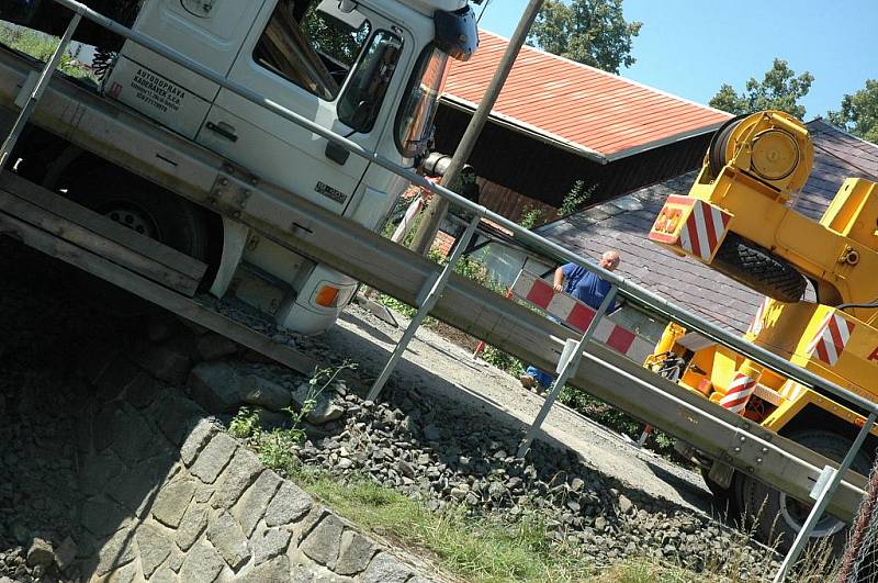 Kamion naložený hutním materiálem se pokoušel projet po provizorním mostě ve Volfarticích. Utrhla se s ním krajnice a museli jej vyprostit jeřábem. 