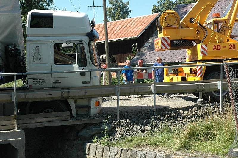 Kamion naložený hutním materiálem se pokoušel projet po provizorním mostě ve Volfarticích. Utrhla se s ním krajnice a museli jej vyprostit jeřábem. 