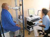 Pacient  usazený ve vyšetřovací kabině bodypletysmografu provádí různé dechové manévry podle pokynů zdravotní sestry.