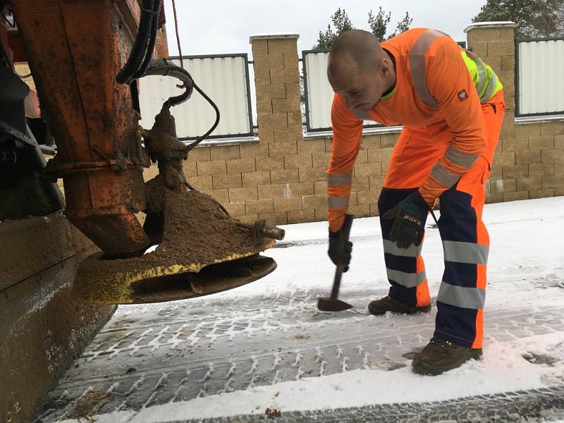 Řidič posypového vozidla Karel Rampouch oklepává zatvrdlý posyp. 