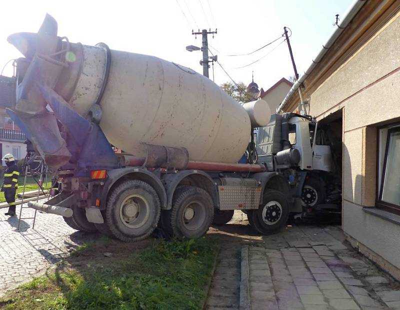 Míchačka slisovala auto v Brankovicích na Vyškovsku a ještě nabourala rodinný dům. Hasiči museli budovu zajistit.