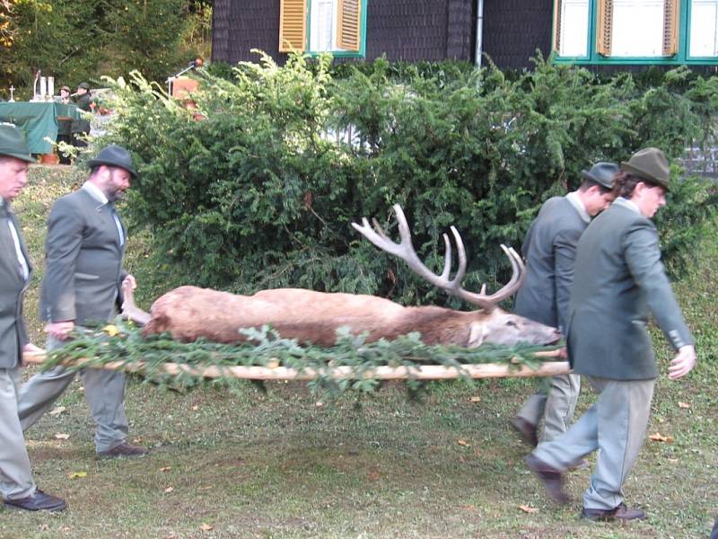 Myslivci nesou jelena, který ležel před oltářem jako trofej lovu.
