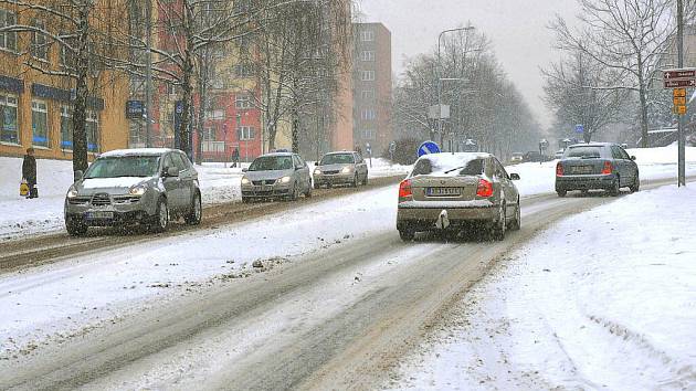 Řidiči projíždějí po zasněžené Lidické ulici v Třinci.