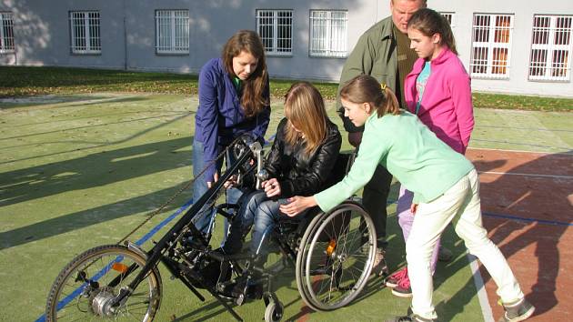 Předání sportovního invalidního vozíku postižené studentce. 